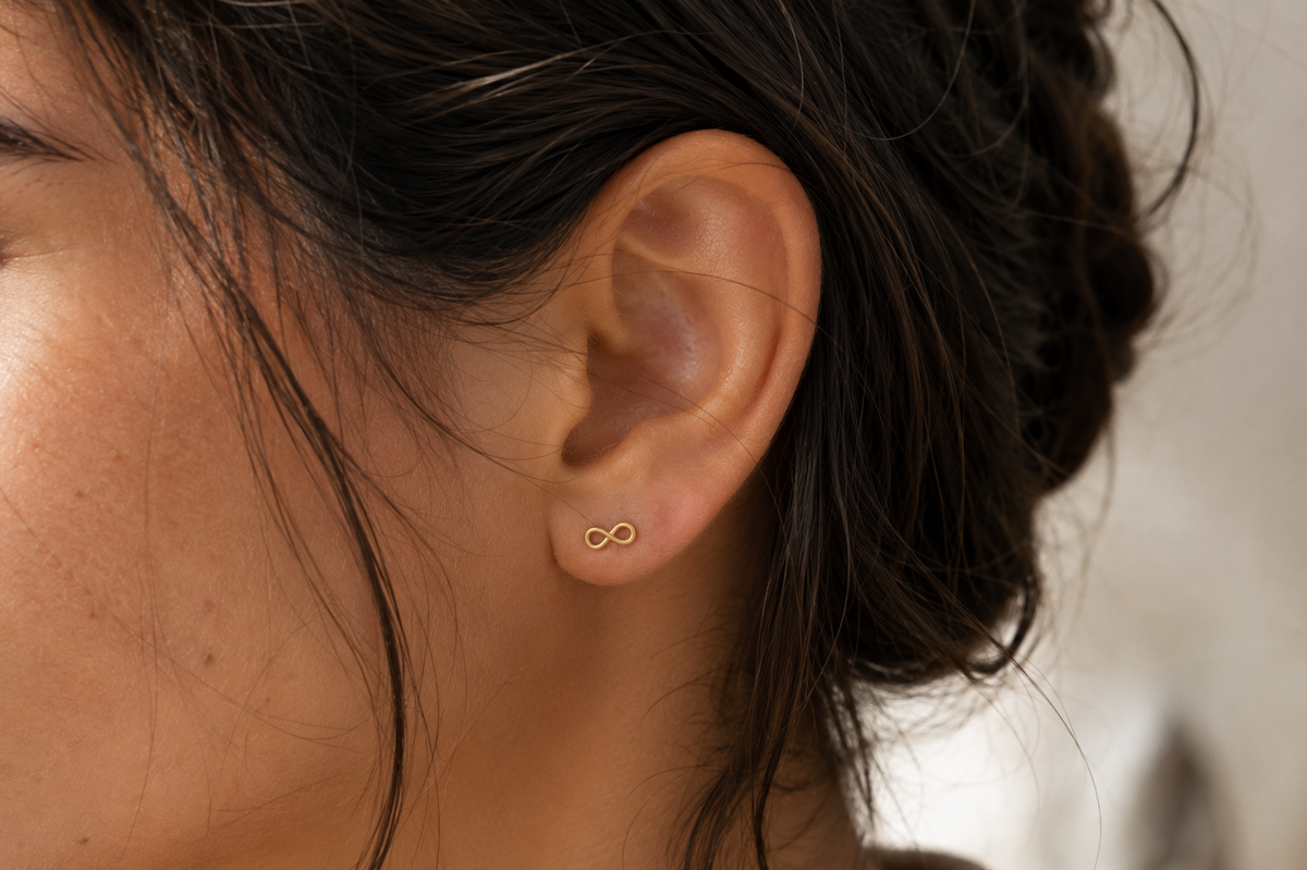 14kt. Gouden Setje Oorstuds met Infinity – Geelgoud – 0.8 mm gedragen door model