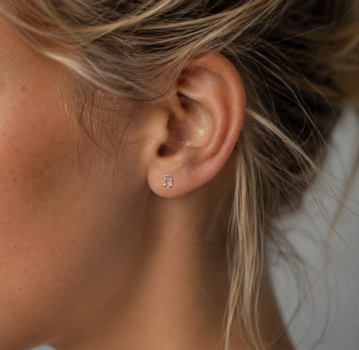 14kt. Gouden Setje Oorstuds met Muzieknoot – Witgoud – 0.8 mm gedragen door model